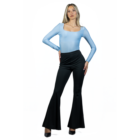 A woman stands confidently wearing a light blue long-sleeve top, black FLARE PANT in stretch fabric with a high waist, and black heels, posed against a white background.